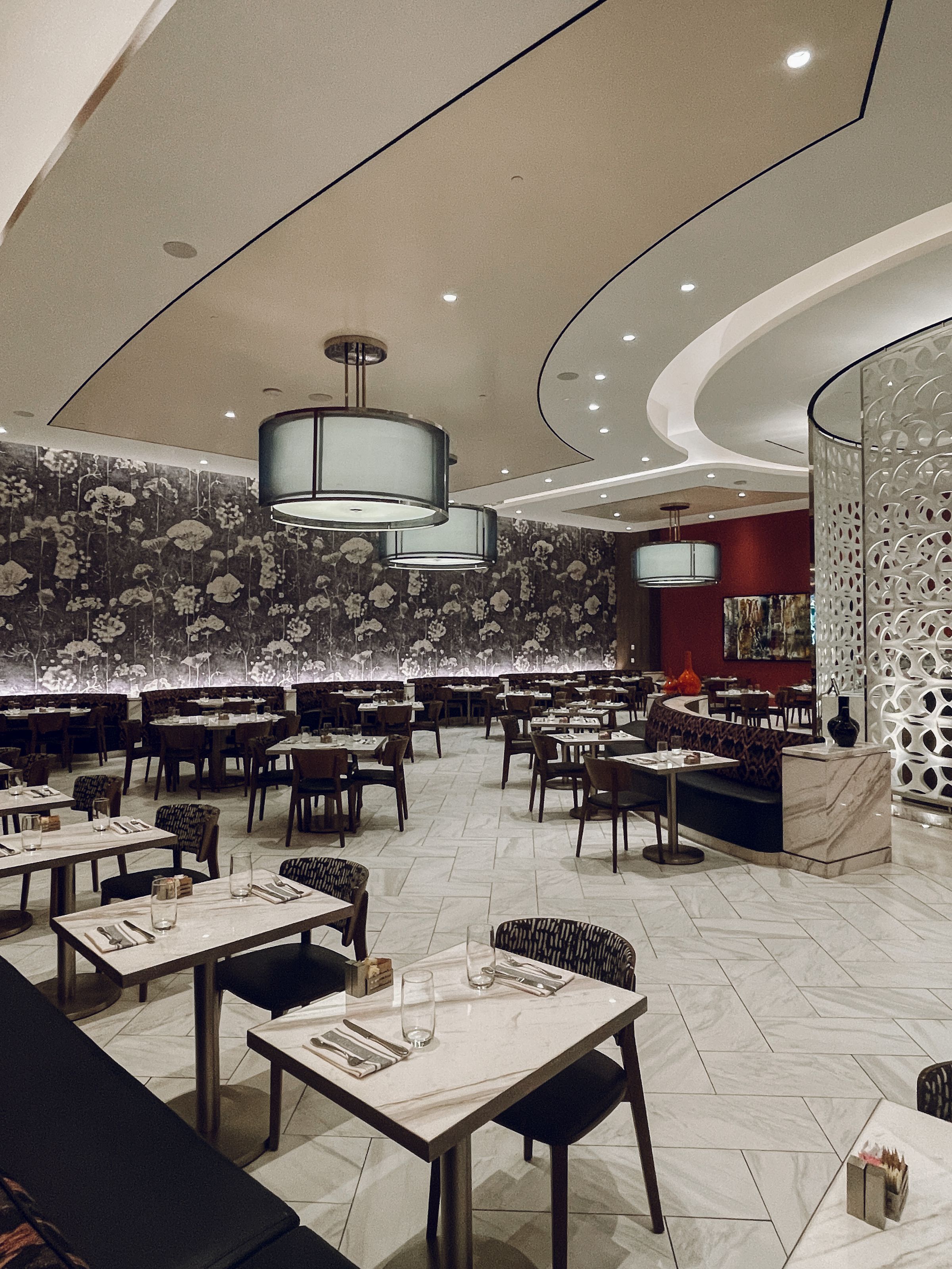 Vista ampla de restaurante com diferentes superfícies, mobiliário e iluminação